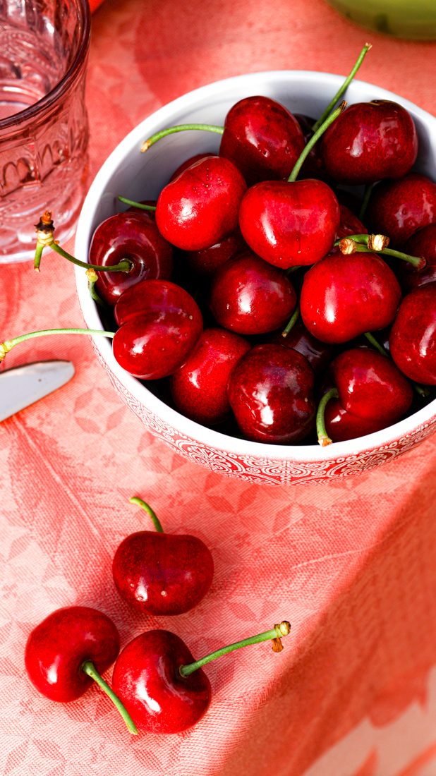 Kirschschale auf rosa Tischdecke von oben