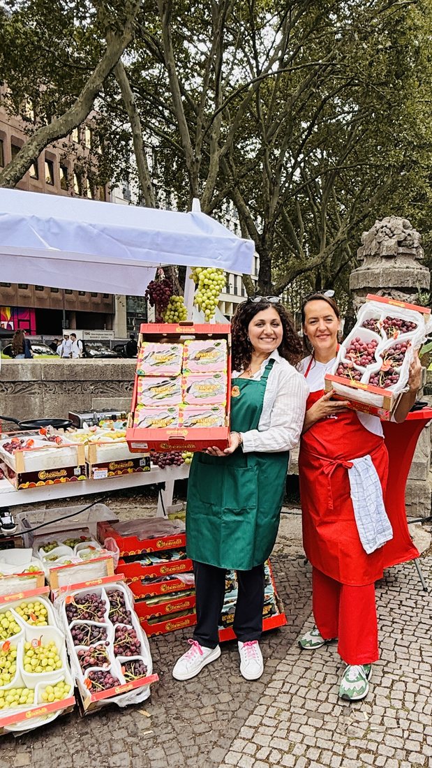 Stefania Lettini und Anna Giacovelli halten Traubenschalen vor dem Stand