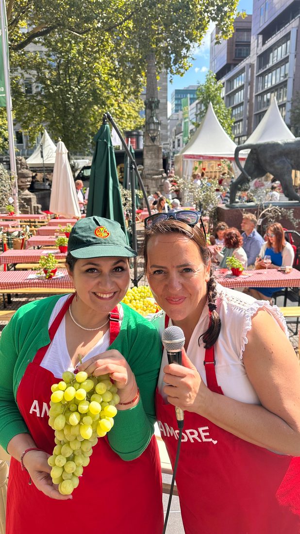 Stefania mit Mikrofon und eine Traube am Giacovelli-Stand