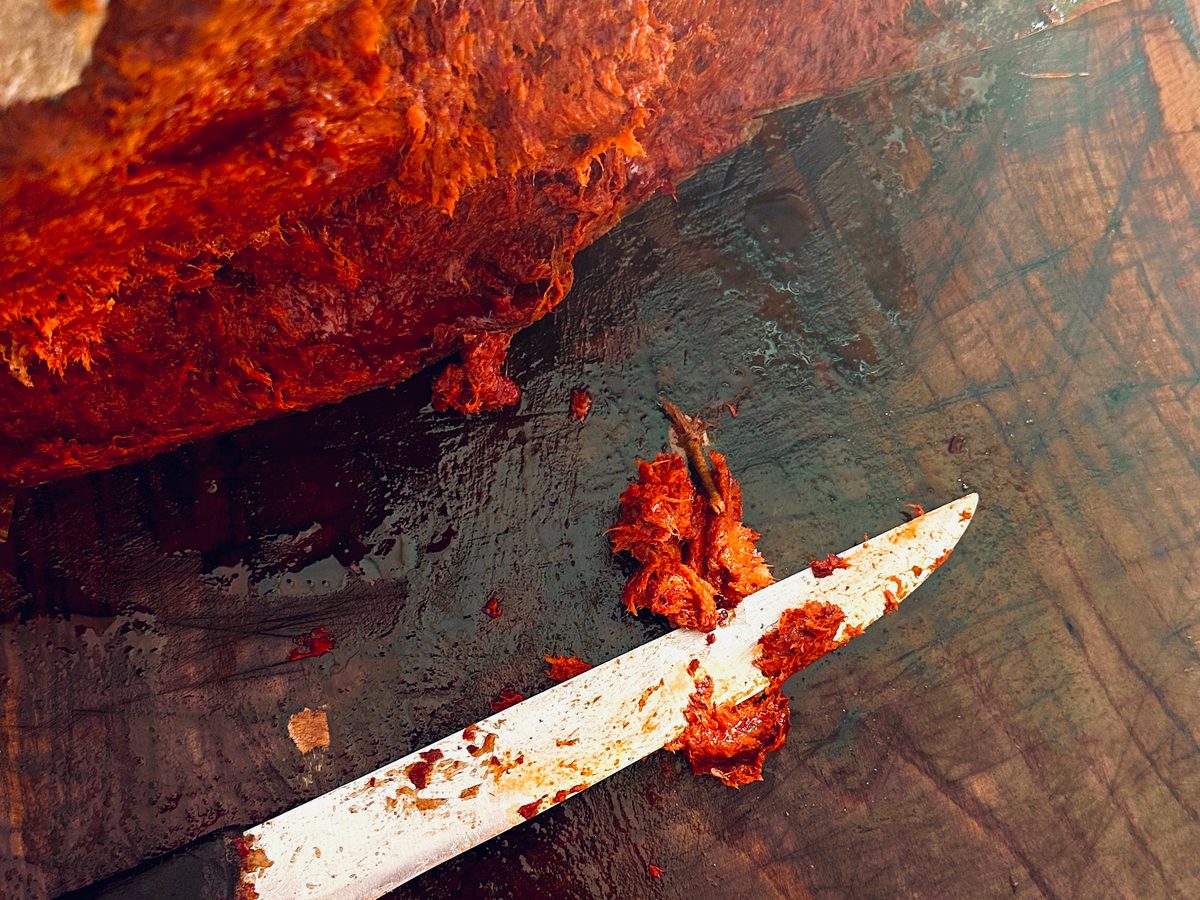 Eine angeschnittene ’Nduja auf dem Holzbrett, daneben das Messer mit ’Nduja