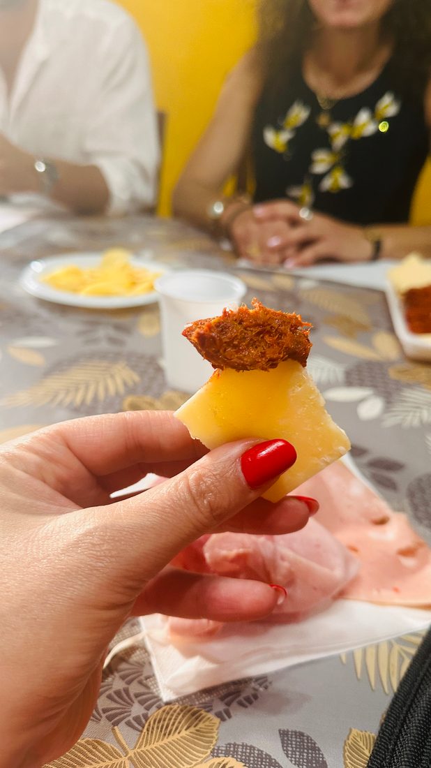 ’Nduja auf einem Stück Käse, zum Probieren in der Hand